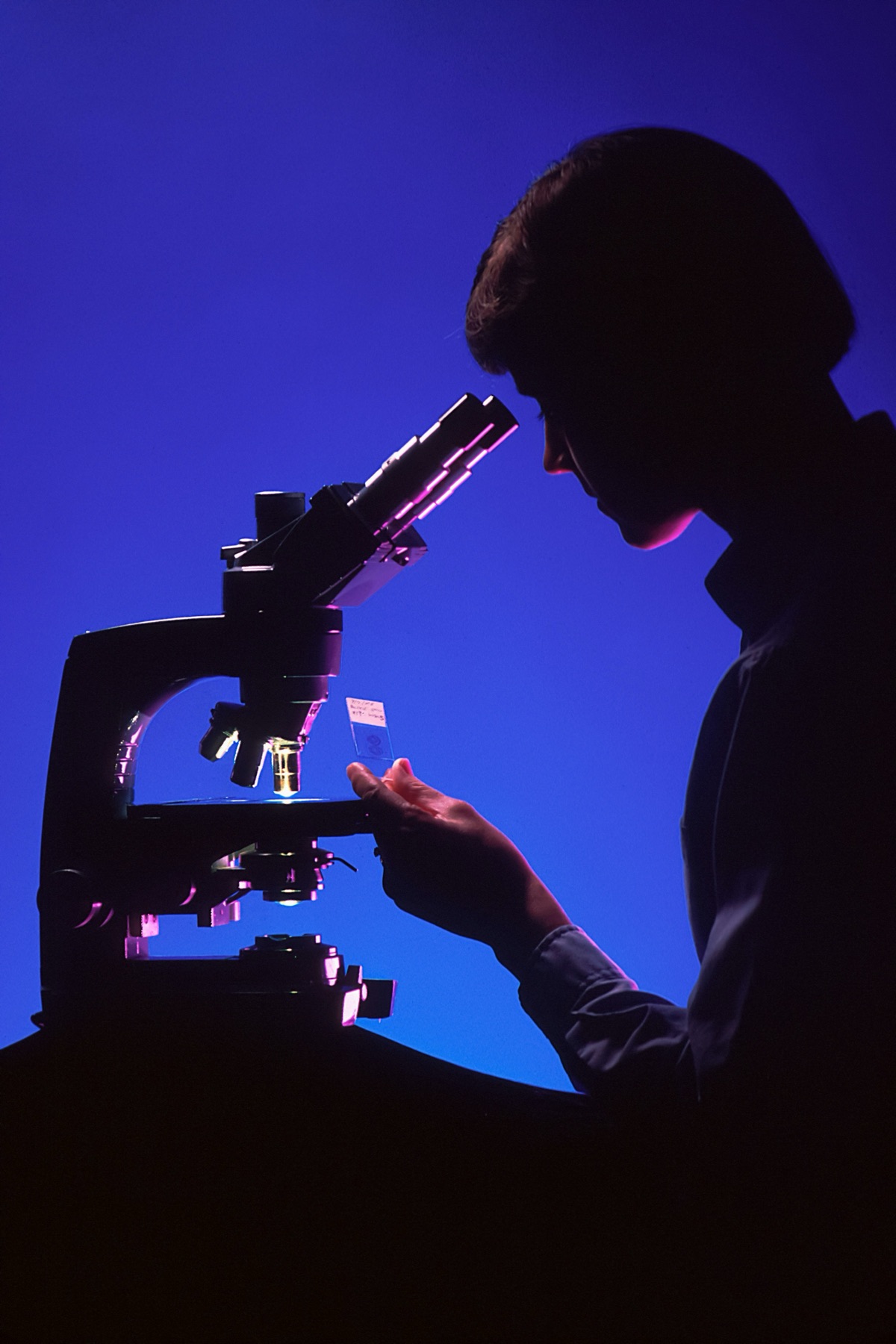 Researcher studying a sample through a microscope